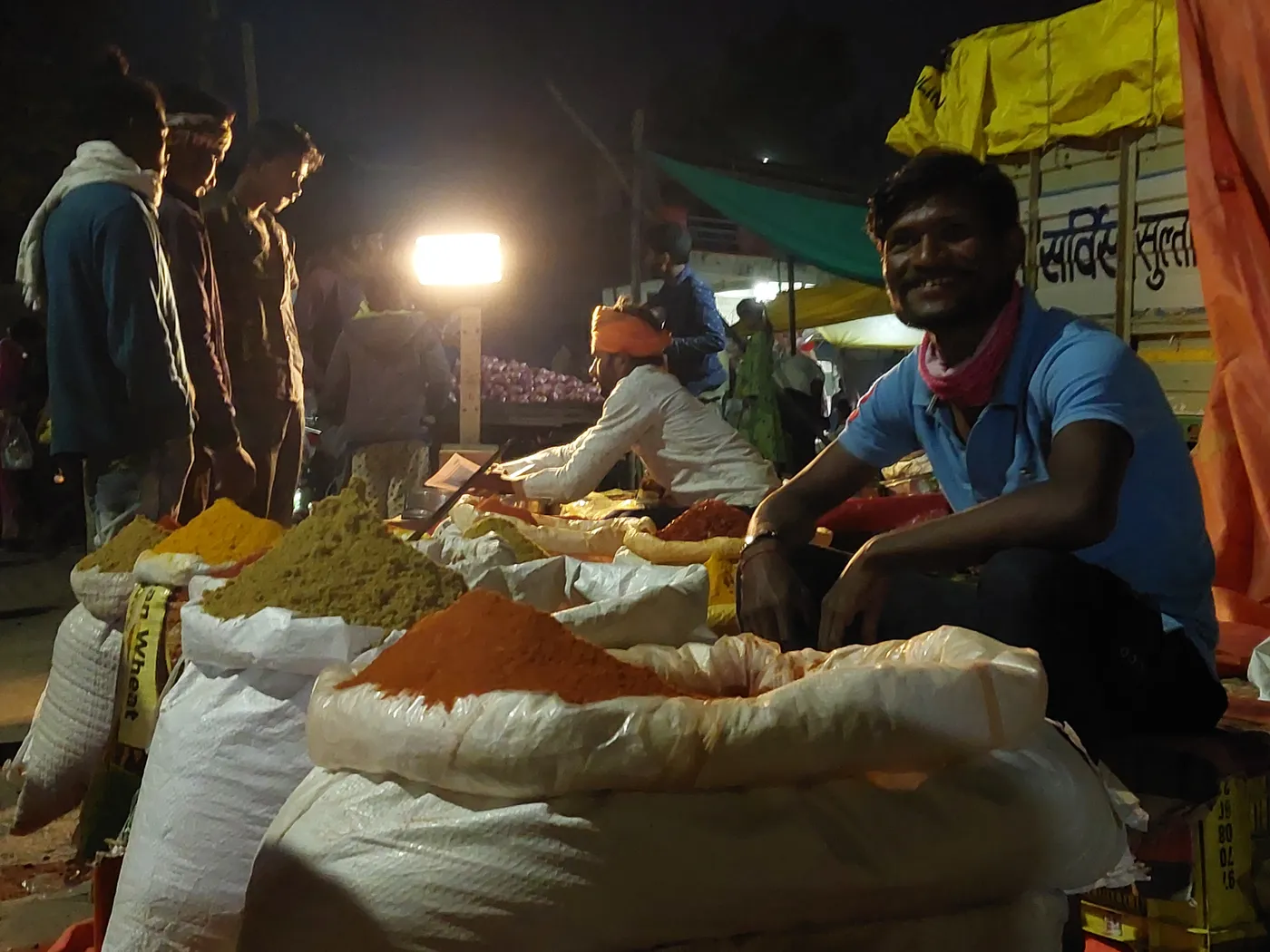 Vendor selling an array of colourful Indian spices at an open-air market